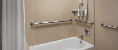 A bathroom with a bathtub, grab bars, and a showerhead.