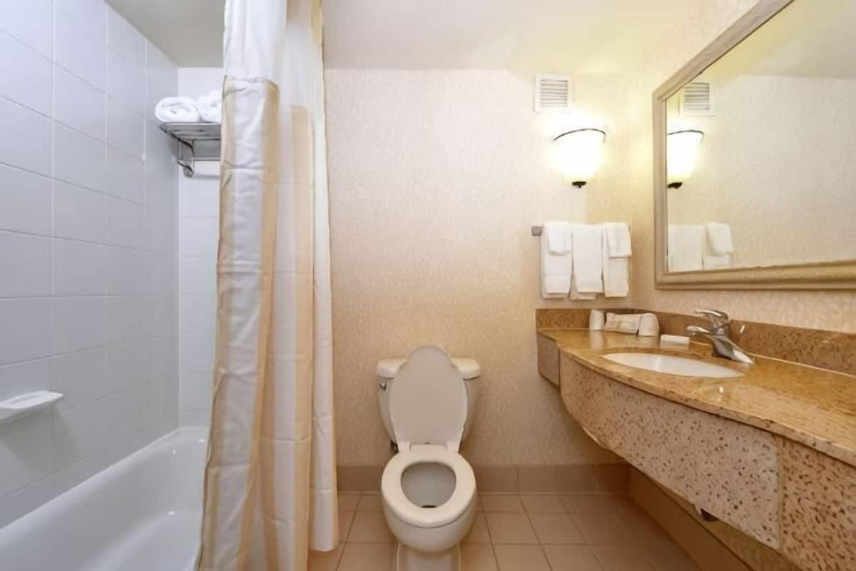 A bathroom with a bathtub, toilet, sink, and mirror.