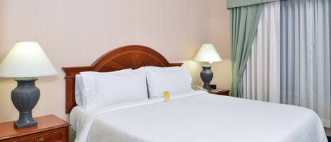 A neatly made bed with white linens, two bedside lamps, and a wooden headboard.