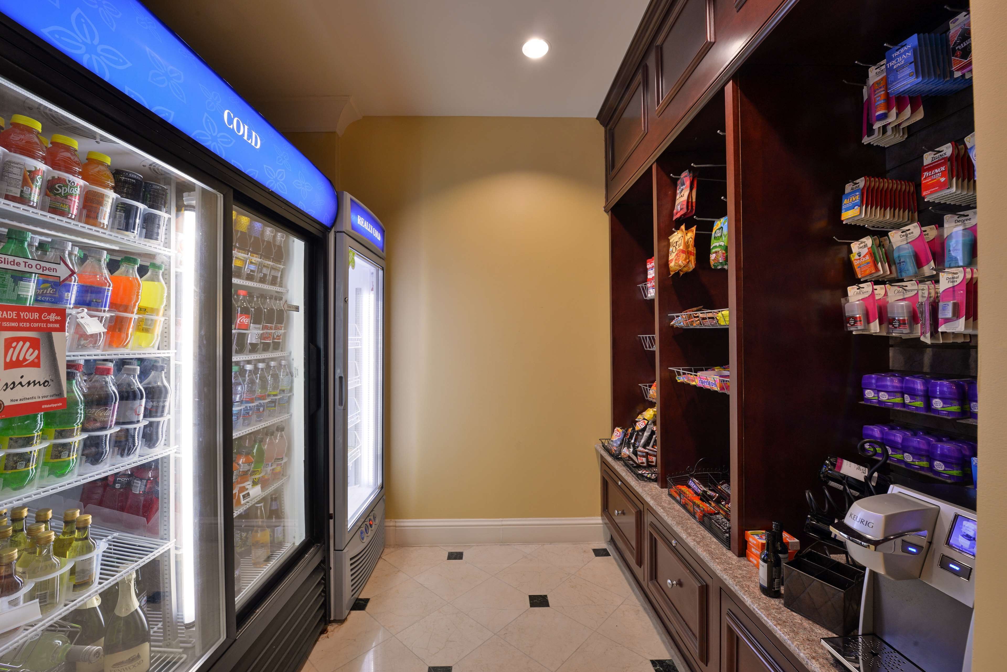 A hotel room with a minibar, a refrigerator stocked with beverages, and a variety of snacks and toiletries.