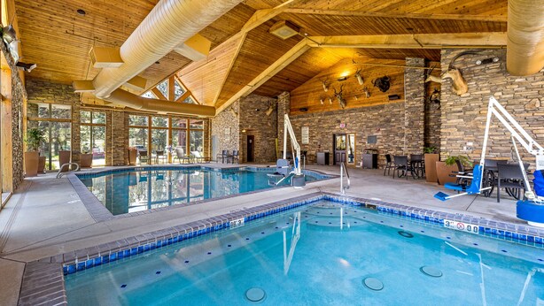 An indoor swimming pool with stone walls and wooden beams. - The Evergreen Hotel (McCall)