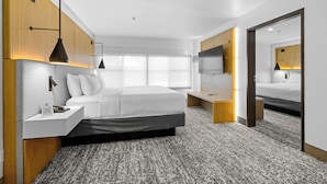 A modern hotel room with a large bed, bedside tables, a TV, and a wooden accent wall. - The Evergreen Hotel (McCall)