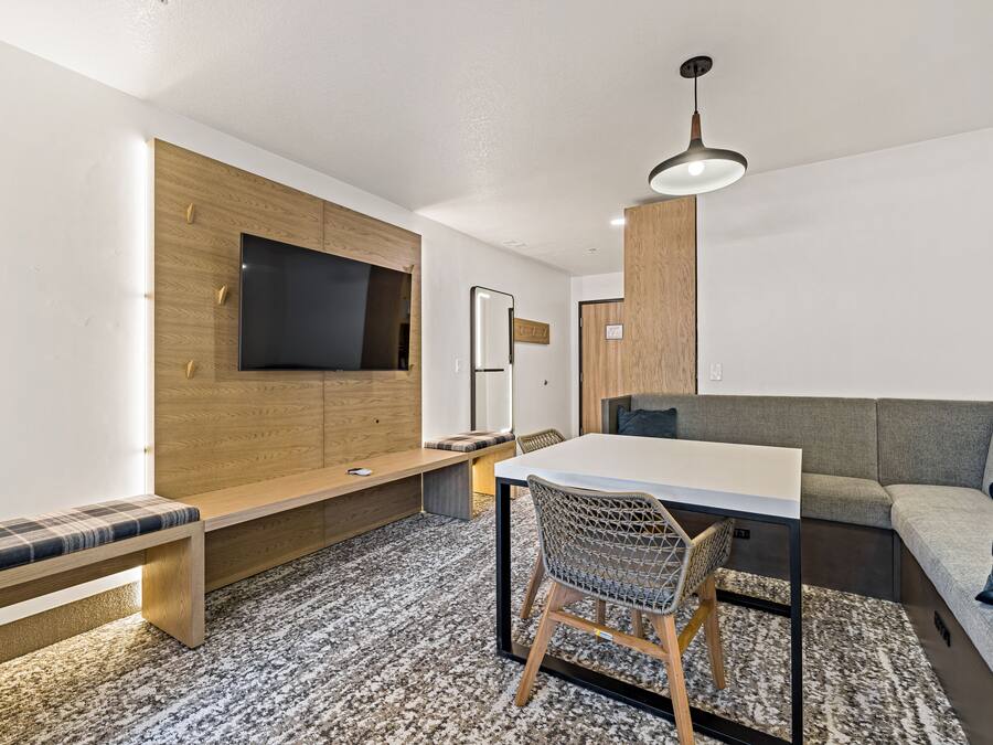 Un salon moderne doté d’un téléviseur à écran plat, de lambris en bois, d’un canapé, d’une table à manger et d’un tapis à motifs.