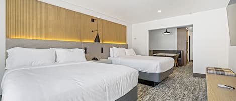 A hotel room with two beds, a desk, and a chair.