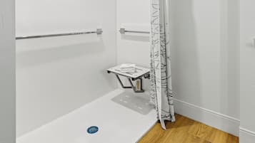 Un baño moderno con ducha, toallero y una mesita.