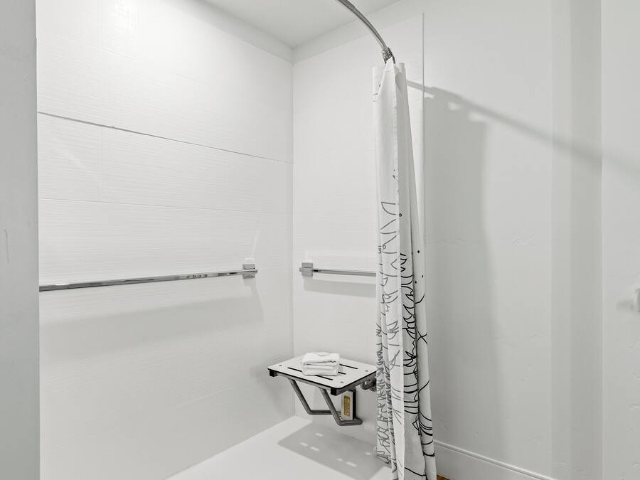Un baño moderno con ducha, toallero y una mesita.