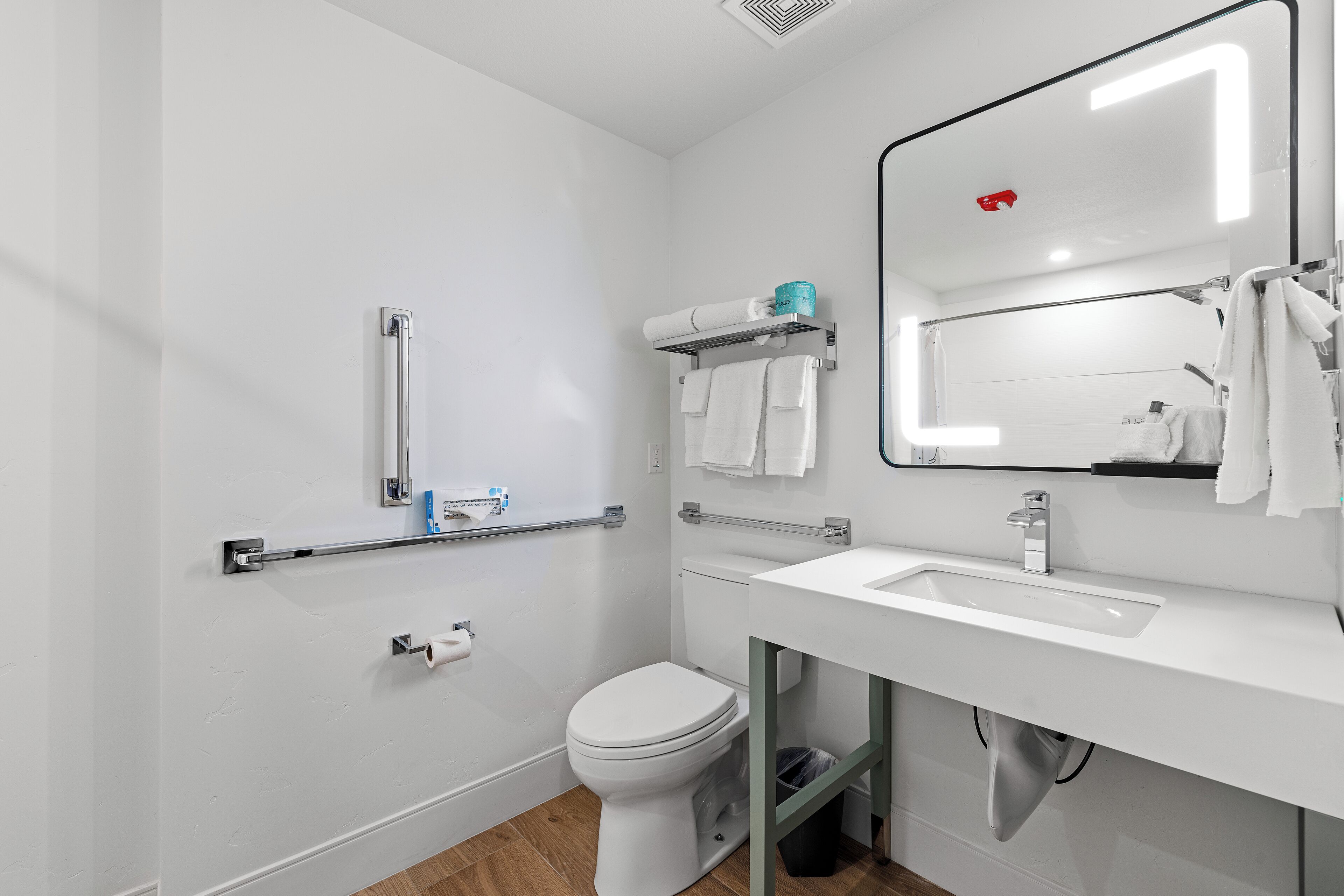 A modern bathroom with a white sink, mirror, and toilet.
