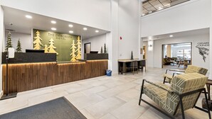 A hotel reception area with a wooden reception desk, a large sign reading "The Evergreen Hotel," and a seating area with patterned chairs. - The Evergreen Hotel (McCall)