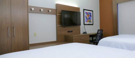 A hotel room with two beds, a desk with a chair, a TV mounted on the wall, and a framed picture.