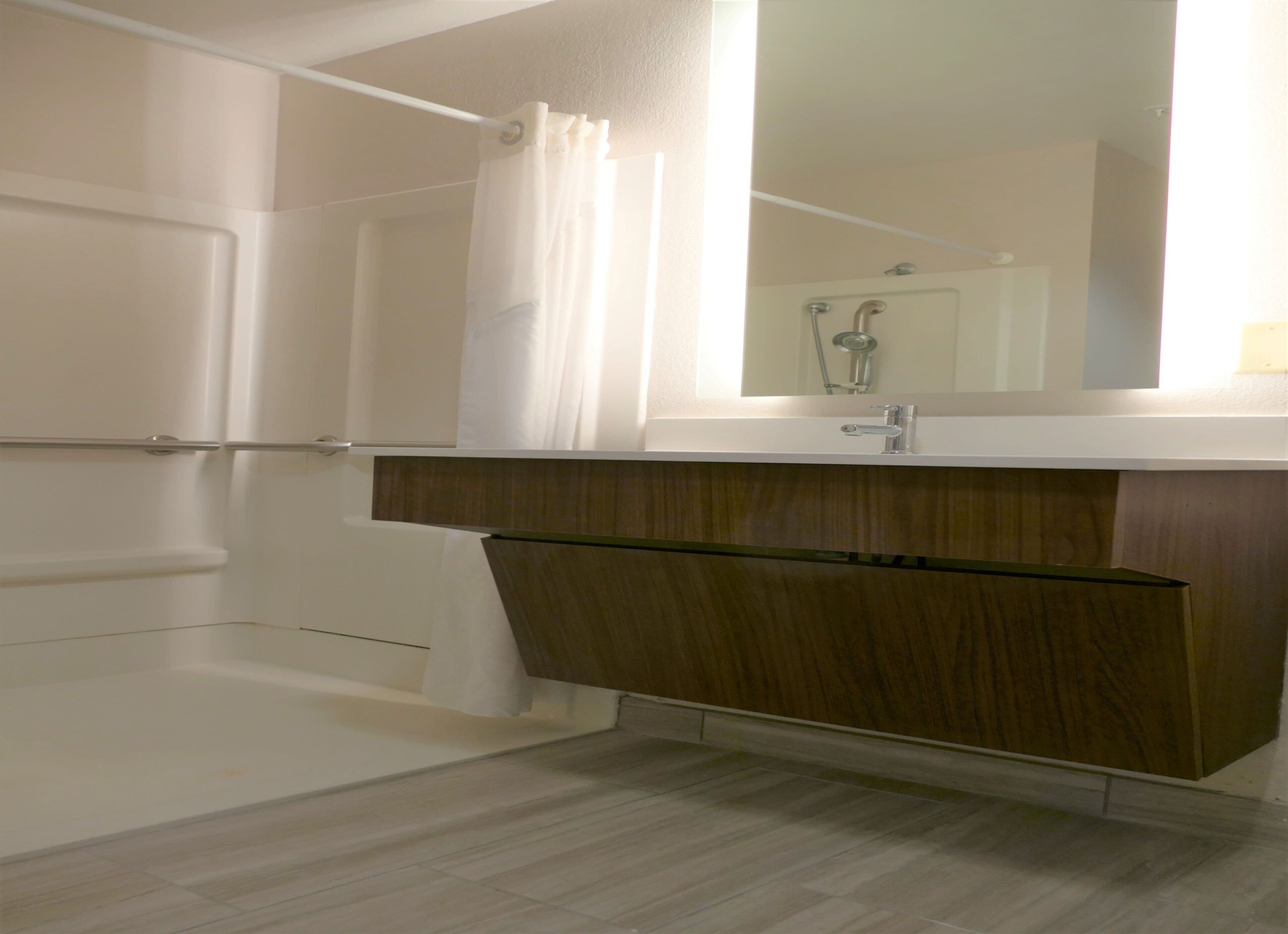 A bathroom with a shower, a sink, and a mirror.