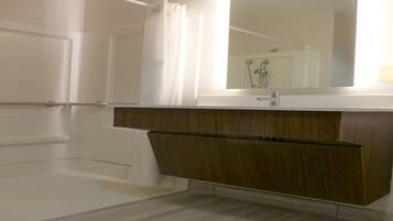 A bathroom with a shower, a sink, and a mirror.
