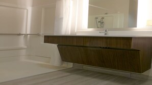 A bathroom with a shower, a sink, and a mirror.