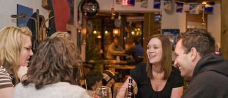 A group of people sitting around a table in a restaurant with wooden beams and banners on the wall.