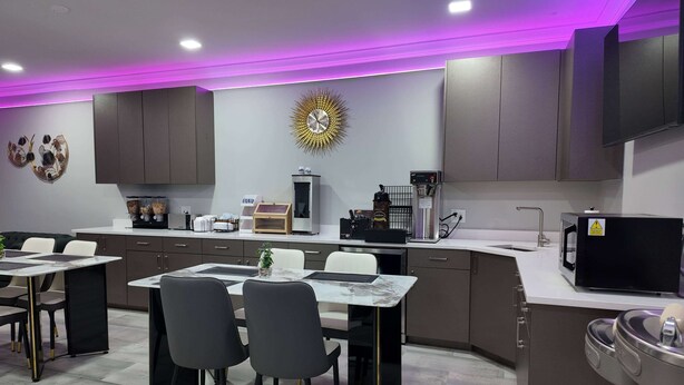 Una cocina moderna con gabinetes grises, encimera de mármol y un comedor con sillas negras y una mesa blanca.