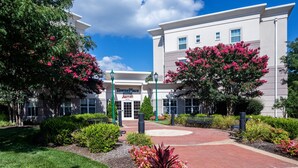 A TownePlace by Marriott hotel with a brick pathway, greenery, and a clear sky. - TownePlace Suites by Marriott Springfield (Springfield)