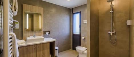A modern bathroom with a wooden vanity, a large mirror, a shower, and a toilet.