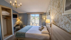 Quarto de hotel com cama, escrivaninha, cadeira e vista para o exterior.