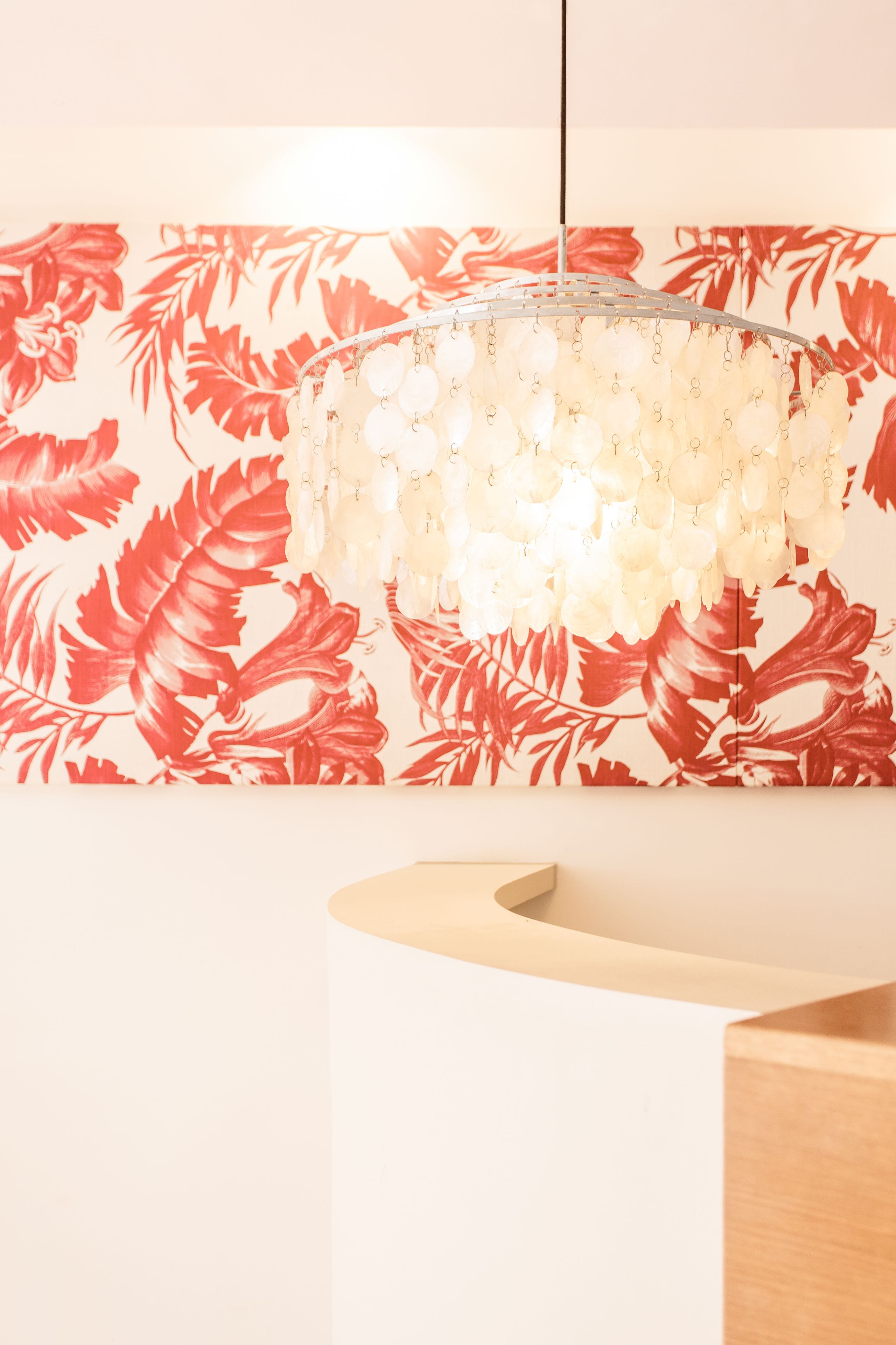 Una moderna recepción con un fondo de papel tapiz floral y una lámpara colgante.