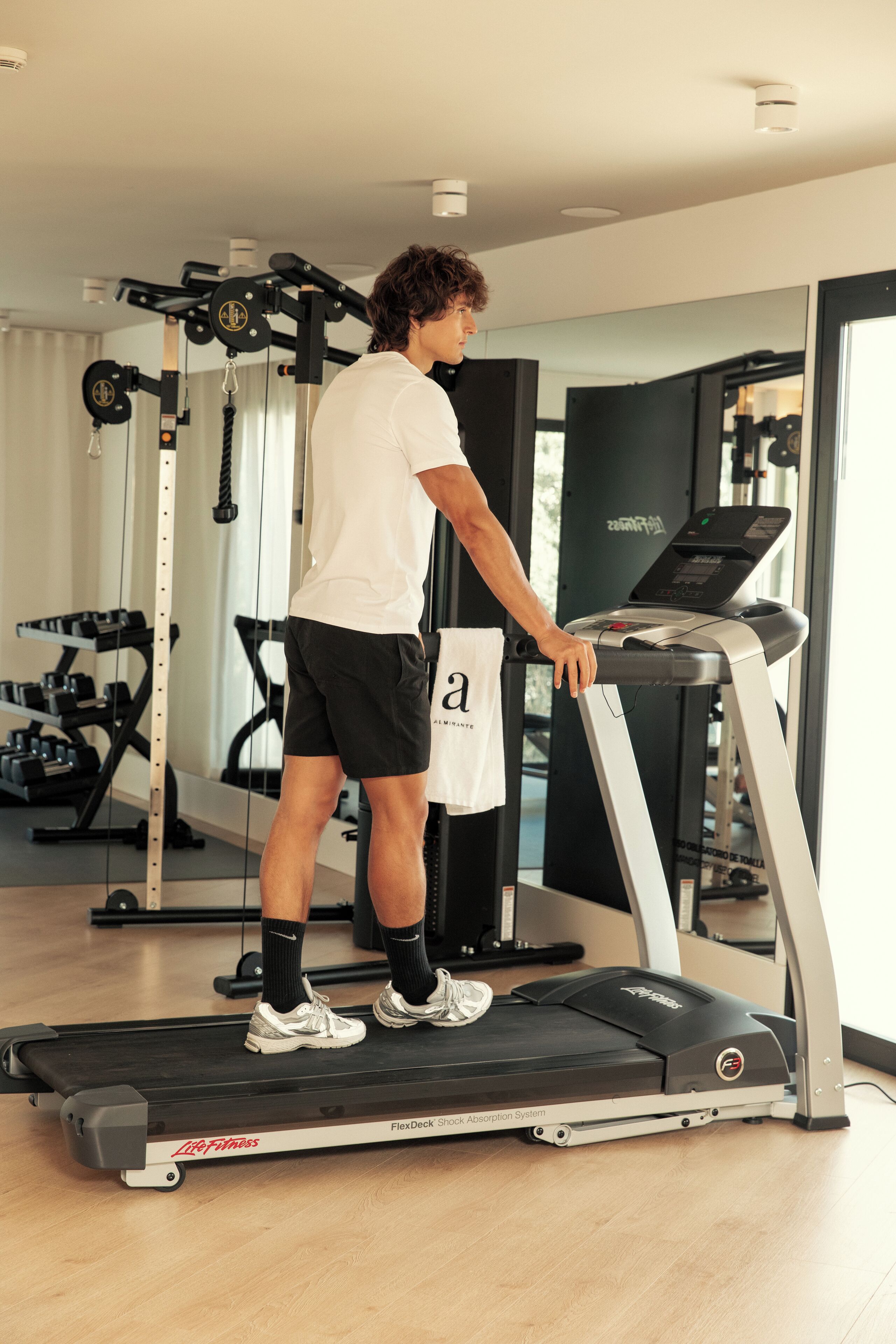 Une personne utilise un tapis de course dans une salle de sport équipée de divers appareils d'exercice.