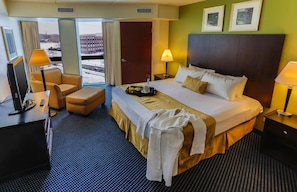Habitación de hotel con cama, escritorio, silla, televisor y ventana con vistas.