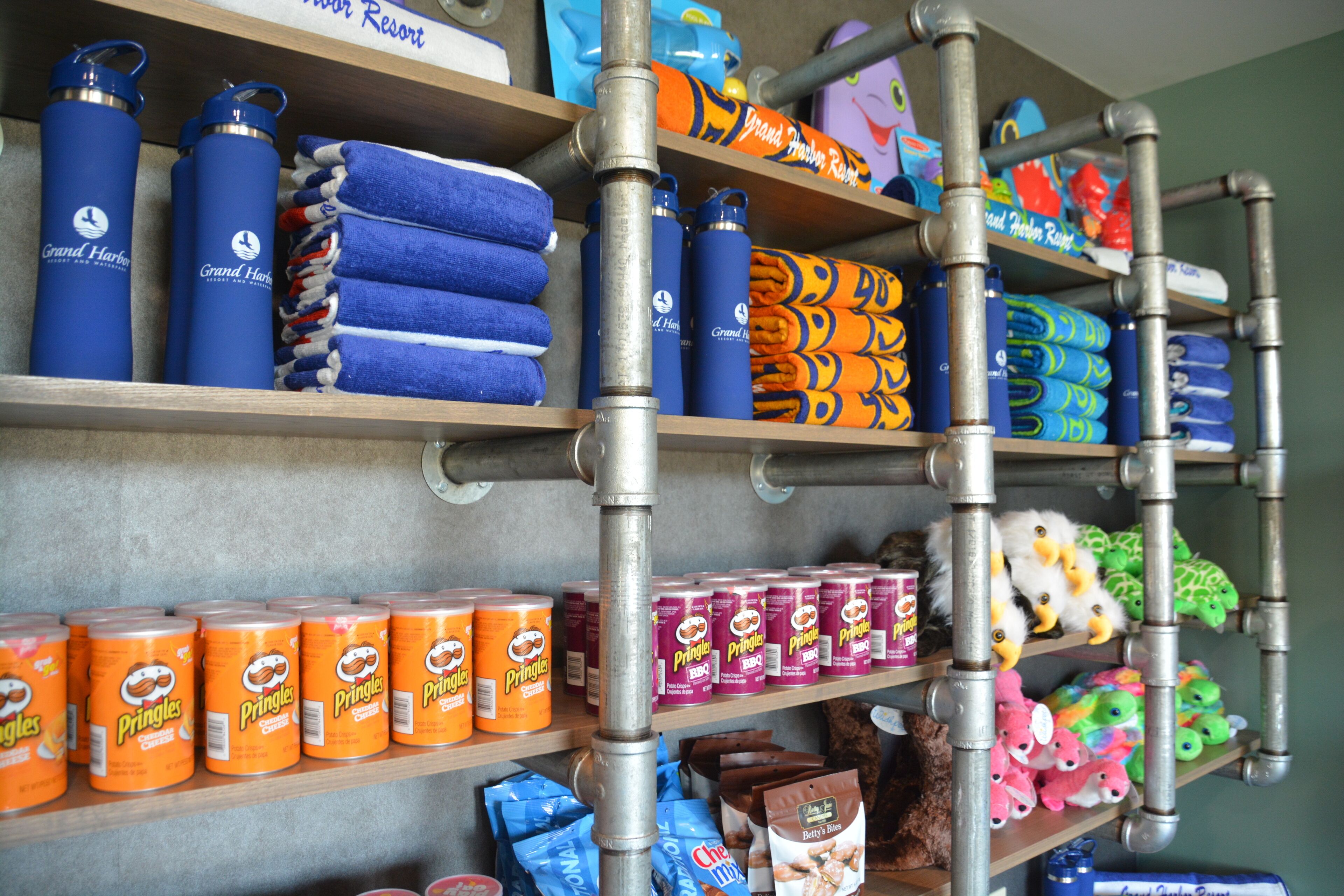 Shelves stocked with various items including towels, water bottles, snacks, and plush toys.