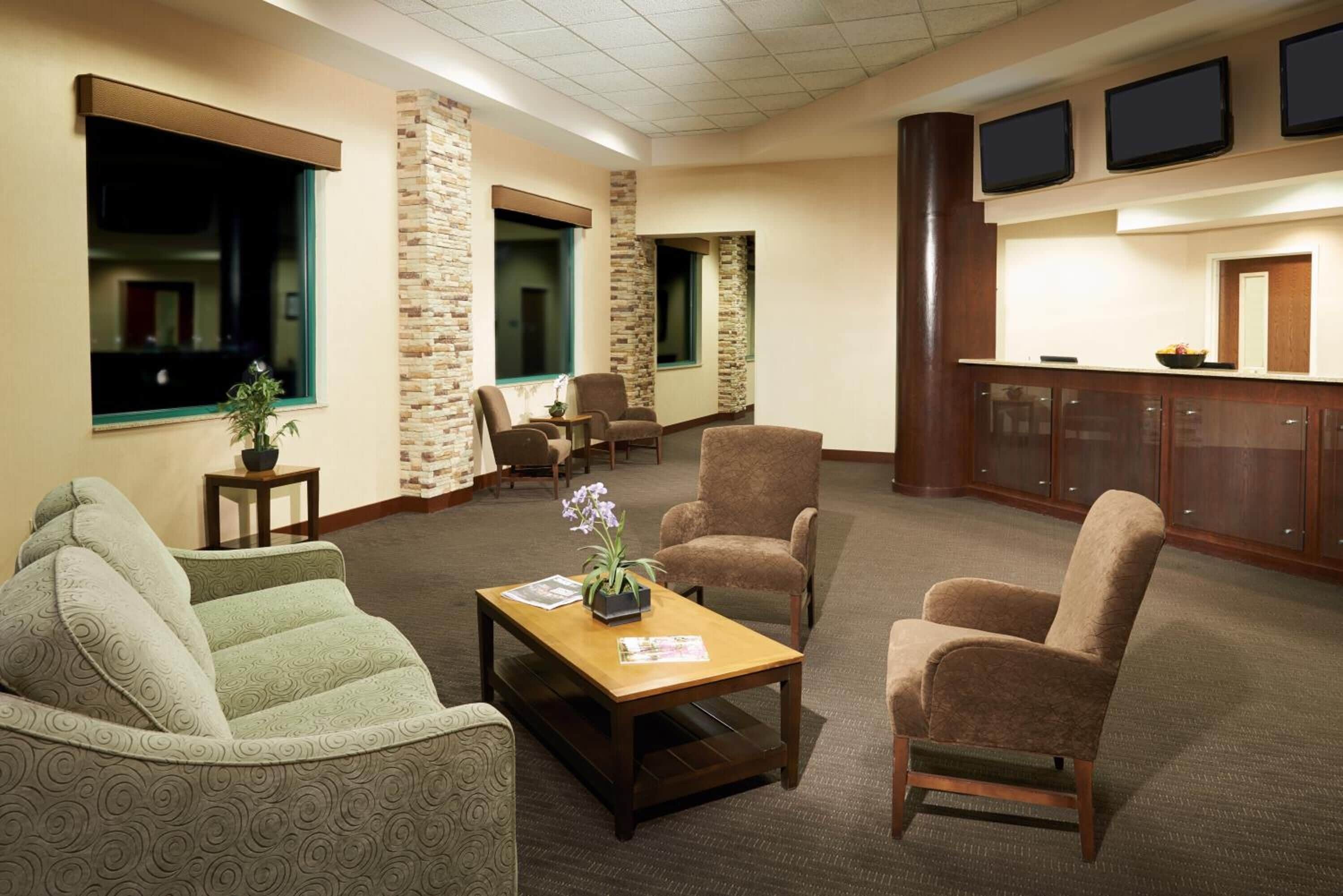 A lobby with a reception desk, seating area, and stone accents.