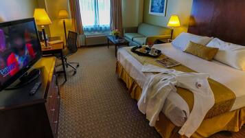 Una habitación de hotel con cama, televisión, escritorio con lámpara, silla y ventana con cortinas.