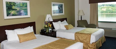 A hotel room with two beds, a nightstand with a lamp, a chair, and two framed pictures on the wall.