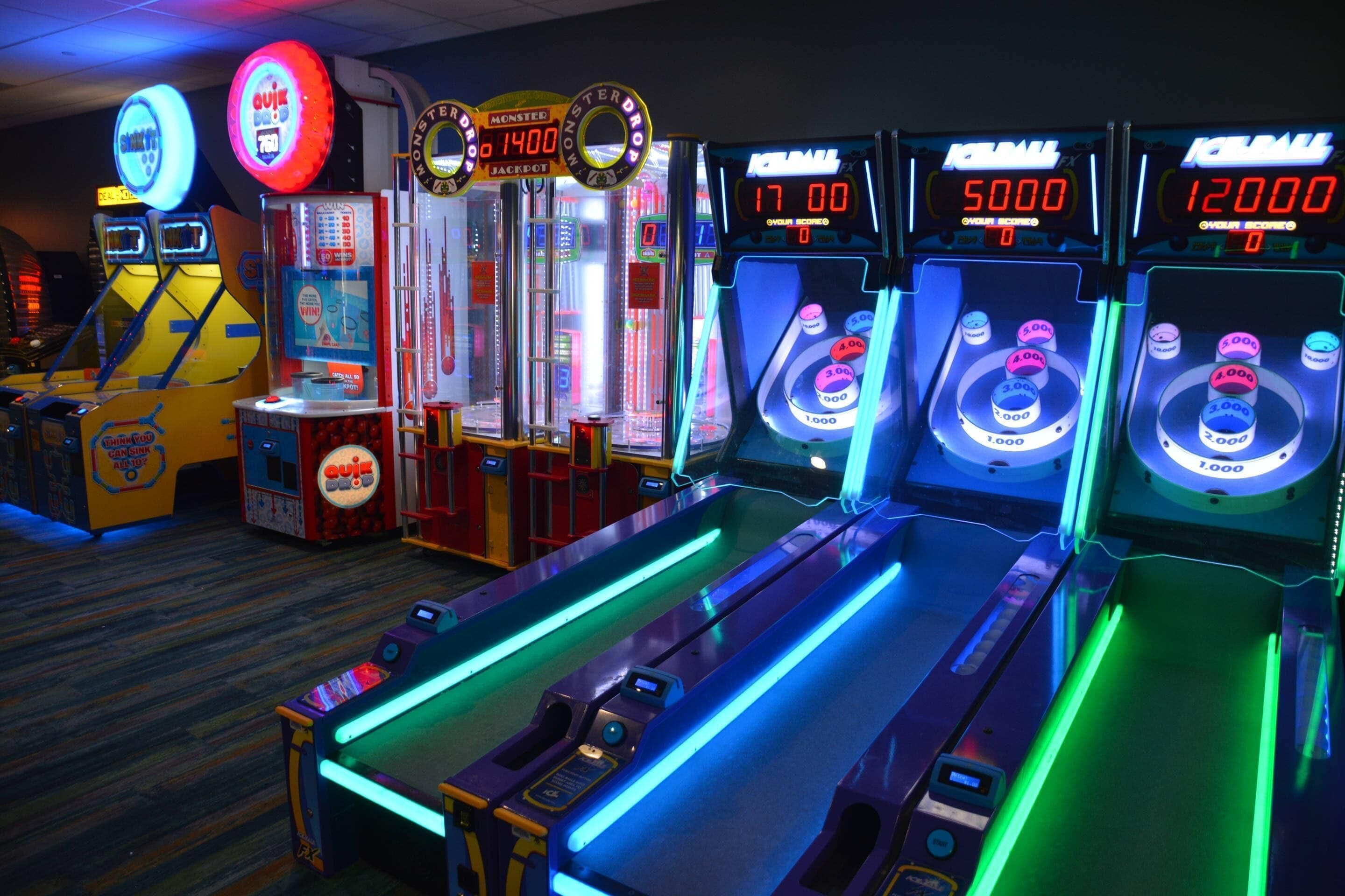 Une rangée de bornes d’arcade dotées d’écrans numériques affichant les scores.