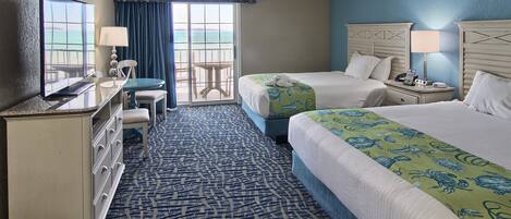 A hotel room with two beds, a desk, a chair, a dresser, and a view of the ocean.