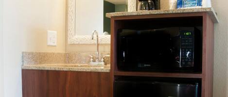 A compact kitchenette with a microwave, a coffee maker, and a small refrigerator.