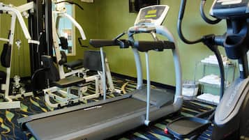 Un gimnasio con cintas de correr, una bicicleta estática y máquinas de pesas.