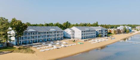 A beachfront hotel with multiple buildings, a sandy beach, and a calm water body.