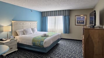 Una habitación de hotel con una cama, un escritorio, un televisor y un aparador.