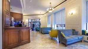 A hotel lobby with a reception desk, seating area, and large windows. - Hotel Capitol (Bucharest)