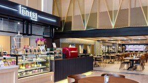 Ein modernes Café mit einer Theke für Backwaren, einer Sitzgelegenheit und einer dekorativen Decke.