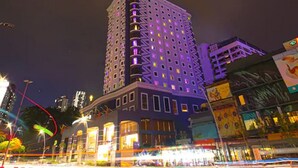 Ein Hochhaus-Hotel mit mehreren Etagen, beleuchteten Fenstern und einem markanten Eingang im Eckbereich.