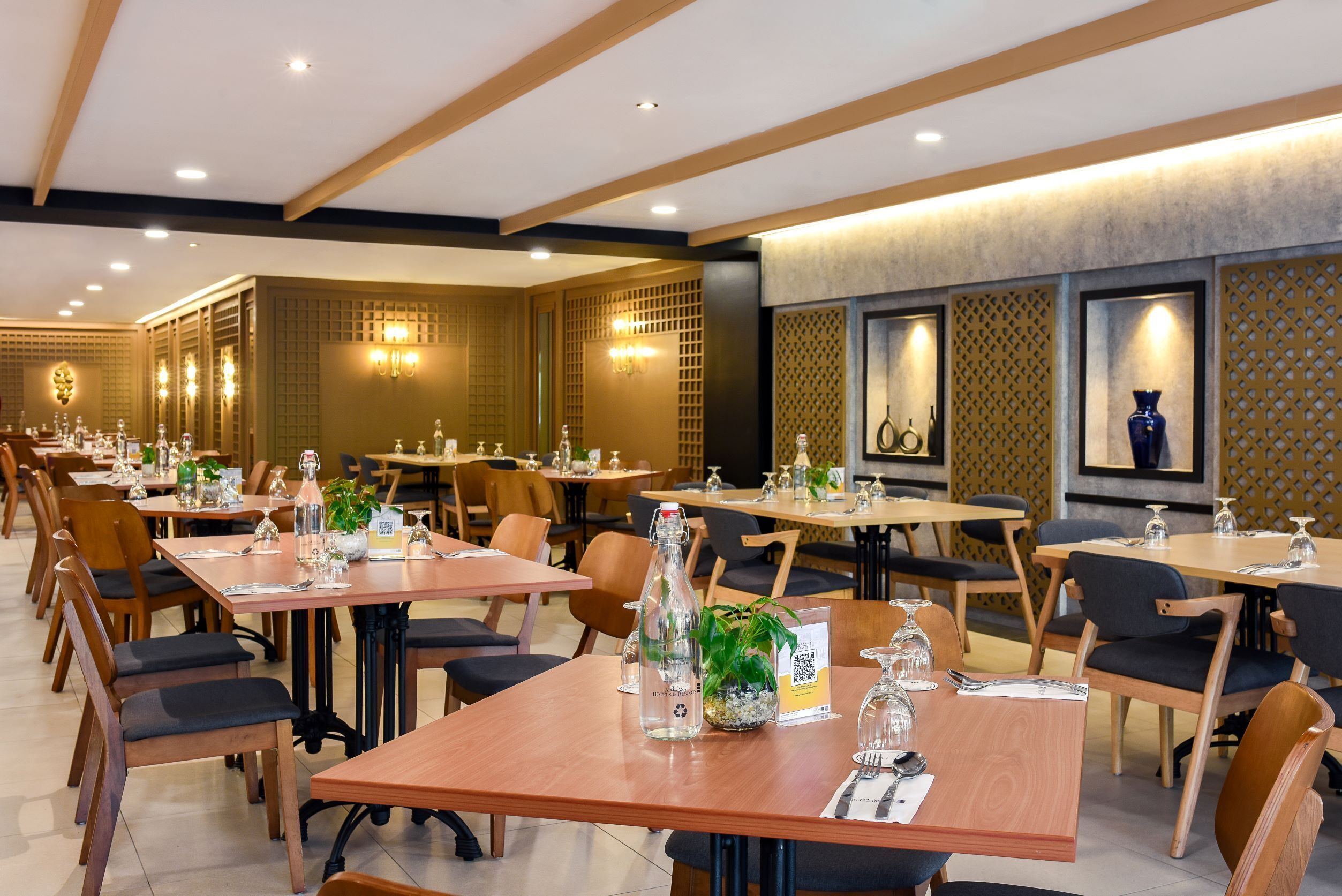 Un ristorante con tavoli e sedie in legno, completo di bicchieri e bottiglie di vino.