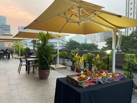 An outdoor dining area with tables and chairs, umbrellas, and potted plants.