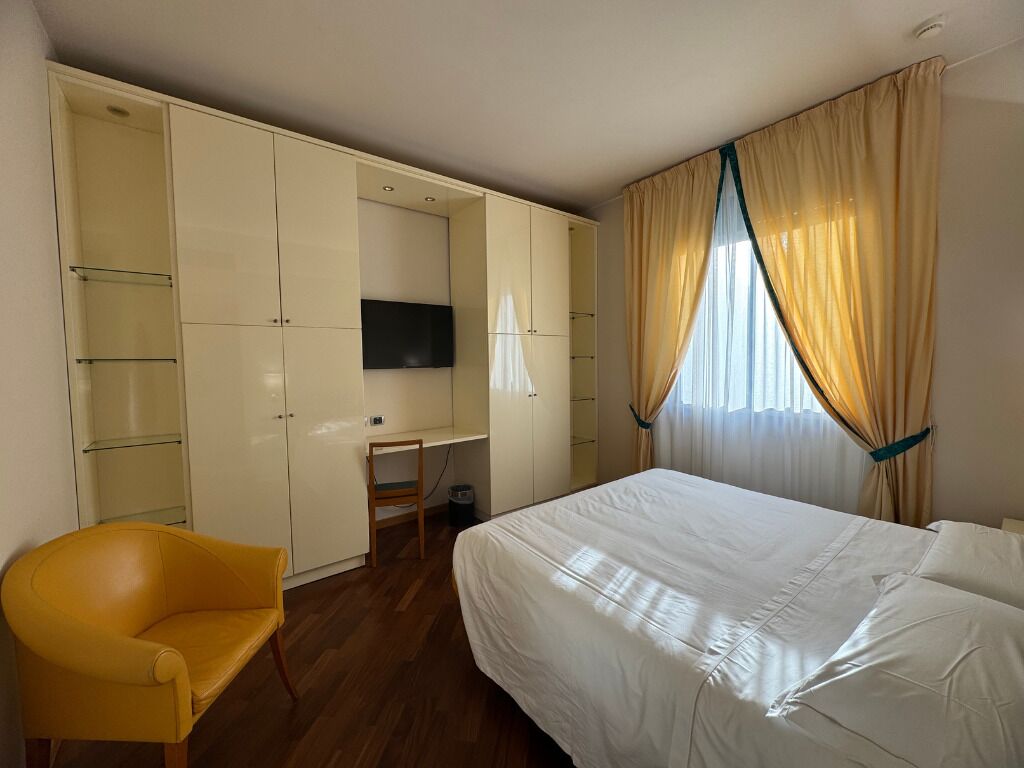 A bedroom with a bed, a desk, a chair, and a wardrobe.