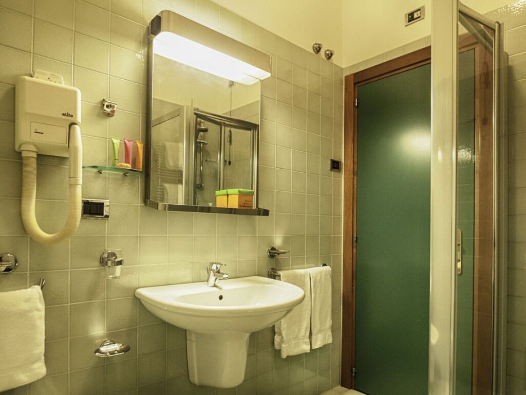 A bathroom with a sink, mirror, and shower.