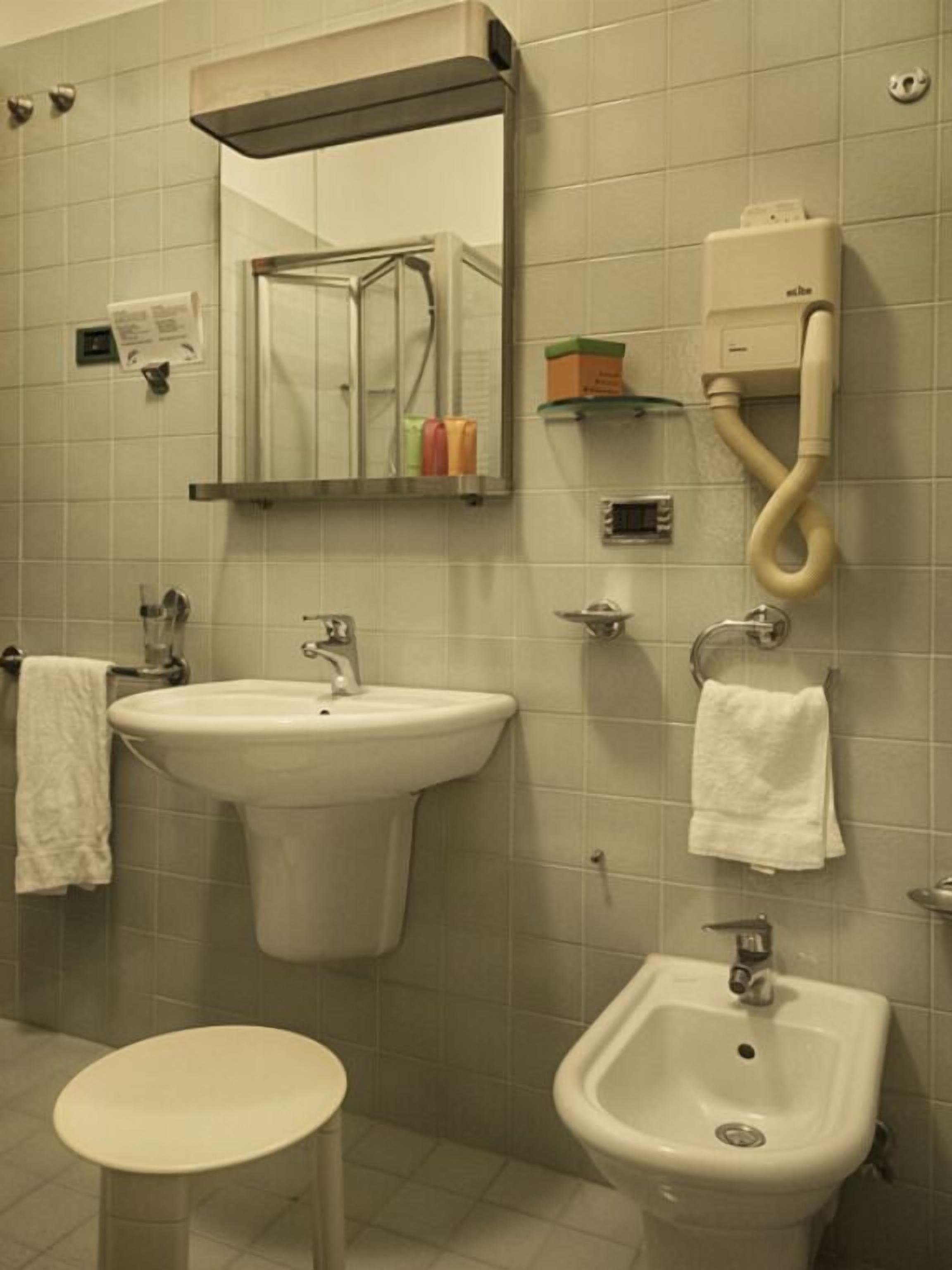 A bathroom with two sinks, a bidet, a mirror, and a towel rack.