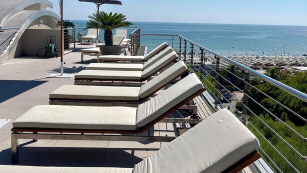 A rooftop terrace with sun loungers and umbrellas overlooking a beach. - Hotel Cristallo (Giulianova)