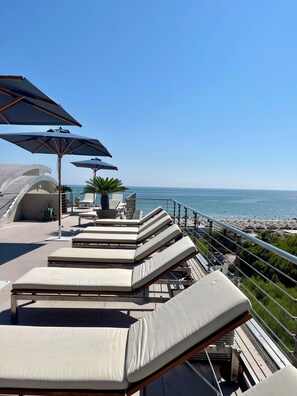 A rooftop terrace with sun loungers and umbrellas overlooking a beach. - Hotel Cristallo (Giulianova)