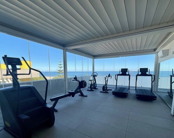 A gym with various exercise equipment and a view of the ocean. - Hotel Cristallo (Giulianova)