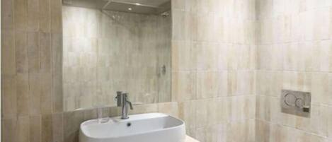 Un baño moderno con un espejo grande, un lavabo sobre encimera, un inodoro y un perchero para toallas.