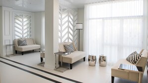 A modern, well-lit room with a sofa, armchairs, and a small table. - Hotel Cristal Marinha (Marinha Grande)