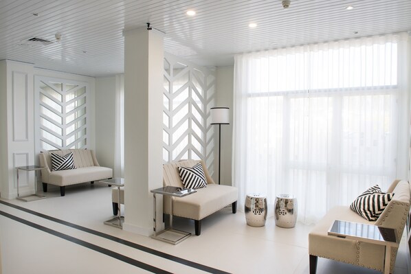 Una habitación moderna y bien iluminada con un sofá, sillones y una pequeña mesa.