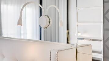 Um sofá branco com tufos e uma mesinha lateral redonda, também branca.