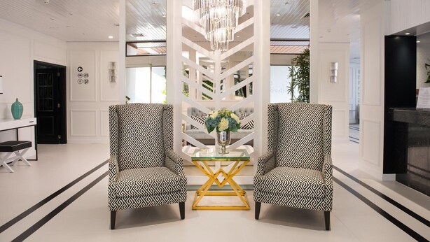 A modern lobby with two patterned armchairs, a glass coffee table, and a chandelier. - Hotel Cristal Marinha (Marinha Grande)
